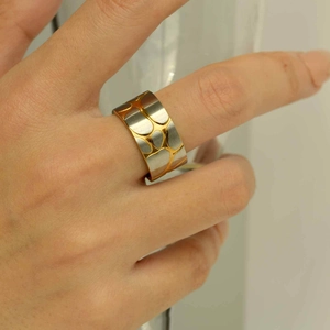 Detail of wide two-tone stainless steel ring with brushed silver pebble inserts on gold band