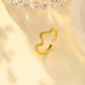 Close-up of wave-shaped gold ring featuring micro-pave cubic zirconia and adjustable opening
