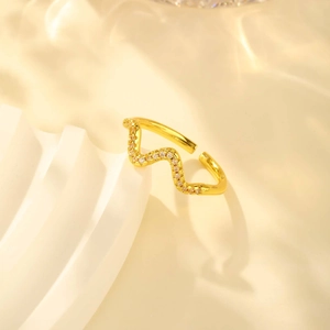 Detailed close-up of a gold wavy zircon ring on an elegant curved artistic pedestal
