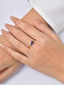 Detailed view of a gold waterdrop ring with blue zircon on a hand for scale