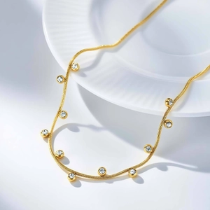 Detail of gold snake chain necklace featuring bezel-set round white zircon crystals