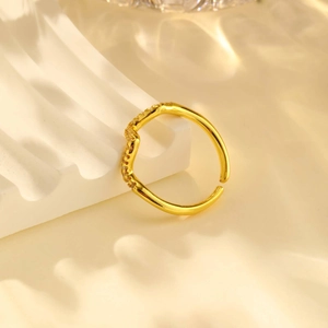 Macro detail of gold wave ring featuring sparkling zircon inlay and textured metal finish