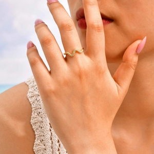 Detailed view of a wave shaped gold ring with shimmering zircon stones on a model hand