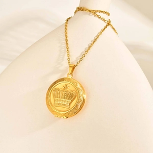 Detalle macro del colgante de relicario dorado con grabado de corona y cadena fina