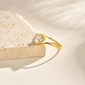 Macro shot of 18K gold plated teardrop zircon ring on a natural stone background