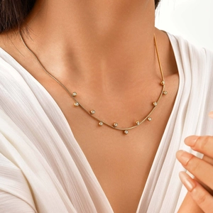 Close-up of golden snake chain necklace featuring nine circular white zircon pendants
