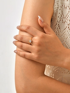Detailed view of an elegant pear-cut zircon gold ring worn by a model on a neutral background