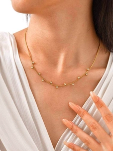 Detail of gold snake chain necklace with round white cubic zirconia on a model