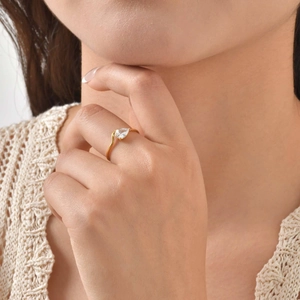 Detailed close-up of a golden pear-shaped zircon ring worn on a finger with elegant style