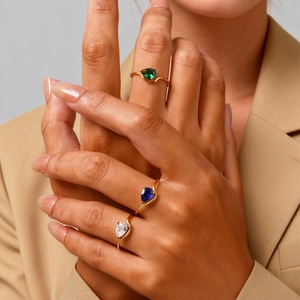 Three-piece gold ring set with pear-cut emerald, sapphire, and clear cubic zirconia