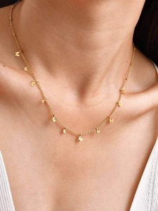 Dettaglio di una collana dorata con ciondoli a farfalla indossata su una modella