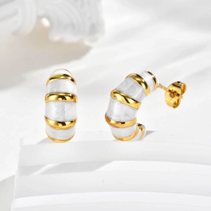Détail de boucles d'oreilles dorées en C avec texture marbre blanc et rayures métalliques