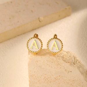 Close-up of gold stainless steel round hoop earrings with white enamel letter A detail