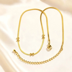 Vue détaillée du bracelet gourmette doré 18K avec nœuds papillon sur fond en soie
