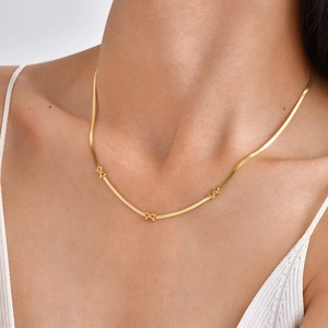 Détail du collier chaîne serpent en or 18 carats avec petits nœuds sur le cou d'un mannequin