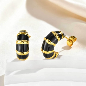Détail de boucles d'oreilles C dorées texture bambou et émail noir sur leur support