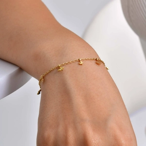 Dettaglio di un bracciale a catena con farfalla dorata al polso per stile di moda