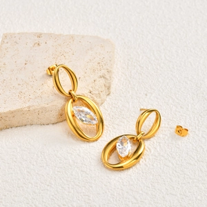 Detail of golden double hoop earrings with marquise cut zircon and polished finish