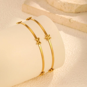 Détails des breloques papillon et fleur en or 18 carats sur bracelets à chaîne plate