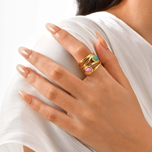 Macro shot of layered gold wavy ring with teardrop turquoise and pink stones