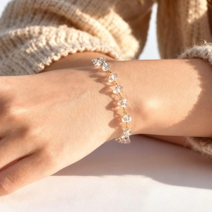 Close-up of minimalist gold bracelet with irregular clear crystals on a model wrist