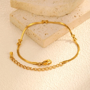 Détail des breloques nœuds en or 18 carats sur une chaîne plate avec fermoir mousqueton