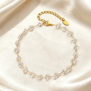 Golden stainless steel anklet with irregular clear crystal beads on elegant satin background