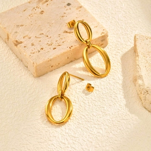 Detail view of double oval minimalist gold earrings on a textured stone display