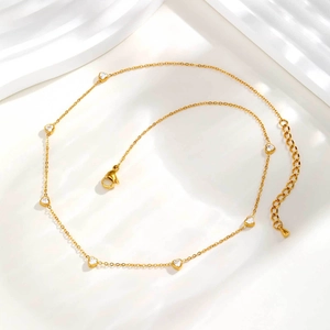 Détail du collier à chaîne dorée avec zircons blancs en forme de cœur et fermoir homard