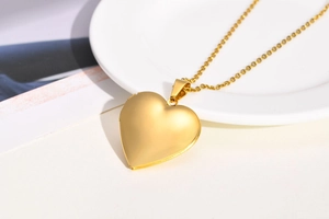 Detail view of heart-shaped gold locket necklace with a matte sandblasted finish