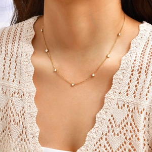 Gros plan d'un collier chaîne dorée orné de plusieurs zircons blancs en forme de cœur
