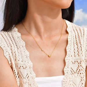 Goldene Schmetterlingskette mit Zirkon an Model vor blauem Himmel getragen