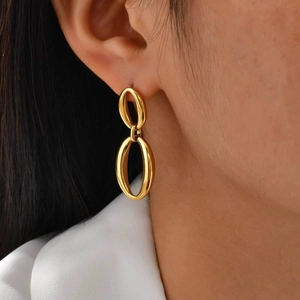 Close-up of elegant gold oval link earrings on model with high-polish metallic finish
