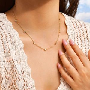 Collier doré avec pendentifs cœurs en zircone sur cou de femme au style épuré