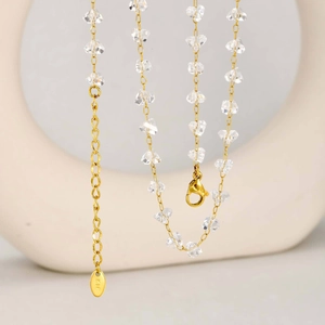 Macro detail of 18K gold chain necklace with clear crystal beads and lobster clasp