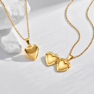 Gold stainless steel heart locket necklace shown in open and closed positions on white rock