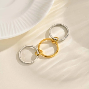Detailed view of three interlocking gold and silver stainless steel rings with water reflection