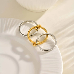 Detailed view of layered silver and gold interlocking stainless steel rings on ceramic