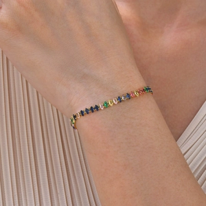 Dettaglio di un bracciale tennis dorato con zirconi colorati a forma di marquise al polso