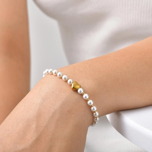 Gros plan d'un bracelet en perles avec pendentif cœur doré sur le poignet d'une femme
