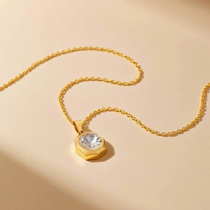 Détail d'un pendentif octogonal doré orné d'un zircon blanc brillant sur une chaîne délicate