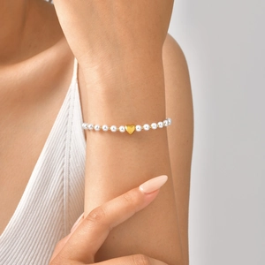 Gros plan détaillé d'un bracelet en perles avec pendentif cœur doré au poignet
