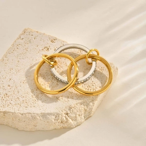Macro view of interlocking gold and silver zircon rings on beige textured stone base
