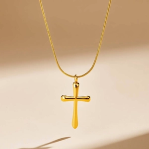Gros plan d'un pendentif croix dorée avec une chaîne serpent plate au fini poli