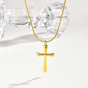 Détail d'un pendentif croix dorée polie avec une chaîne serpent élégante pour femme