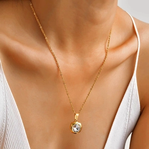 Gros plan d'un collier doré avec pendentif en cristal rond porté par un mannequin