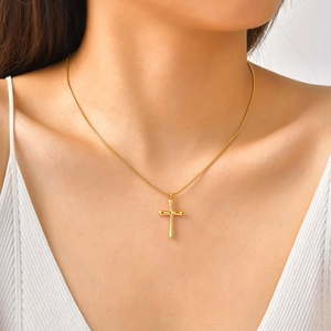 Gros plan d'un pendentif croix dorée brillante sur une chaîne fine pour femme