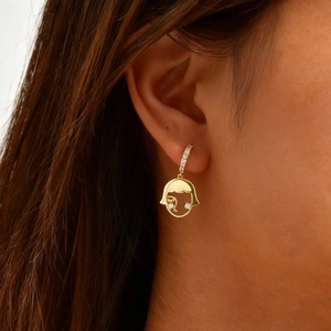 Vue détaillée d'une boucle d'oreille dorée profil de fille sertie de zircons sur l'oreille