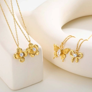 Detalle de collares chapados en oro con colgantes de flores y mariposas con circonita