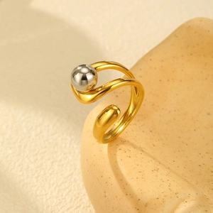 Detailed side view of golden double-layer cross ring with silver bead on textured stand